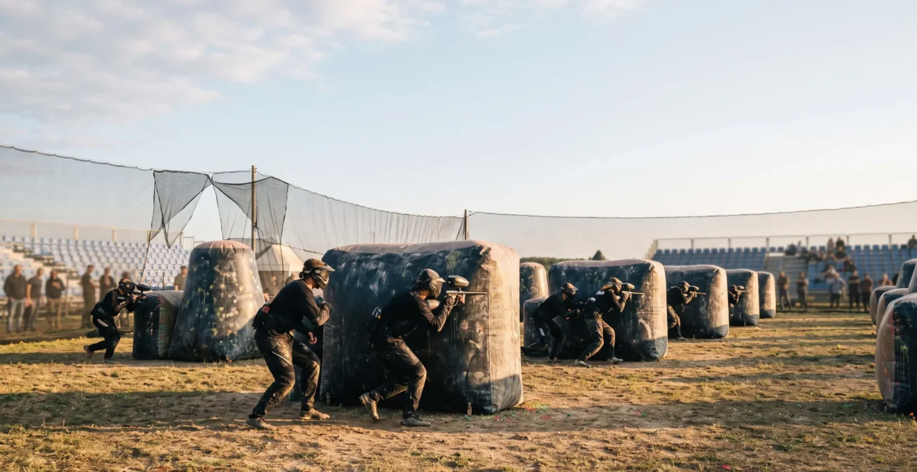 Terrain de compétition de paintball européen avec joueurs en position tactique derrière des bunkers gonflables, symbolisant la hiérarchie des divisions